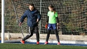 FA-qualified football coach giving individual guidance to a young girl during EFA girls training session in London - girls football programme in London